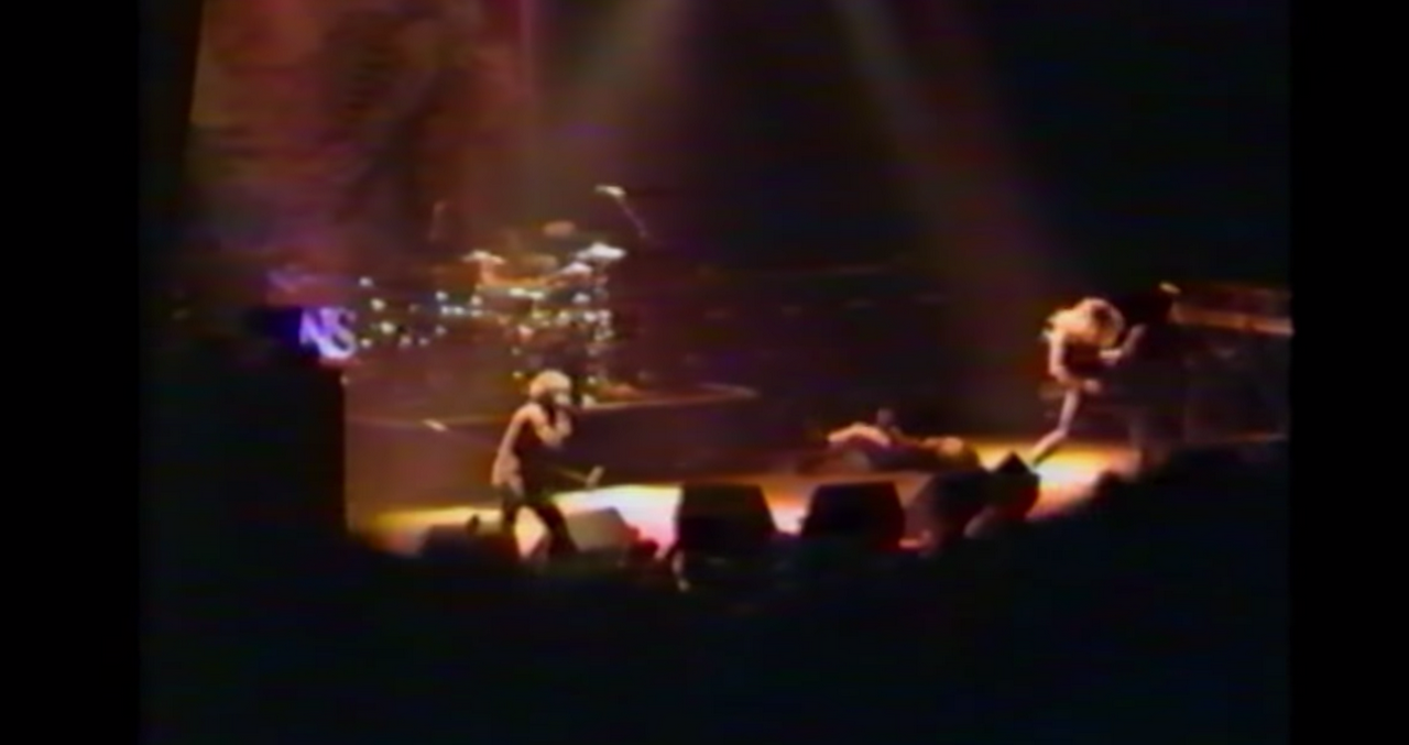Blurry distant photo of Alice in Chains on stage on the Dirt Tour in Tucson. It's smoky and everything is dark except for the stage, where the band is rocking out.
