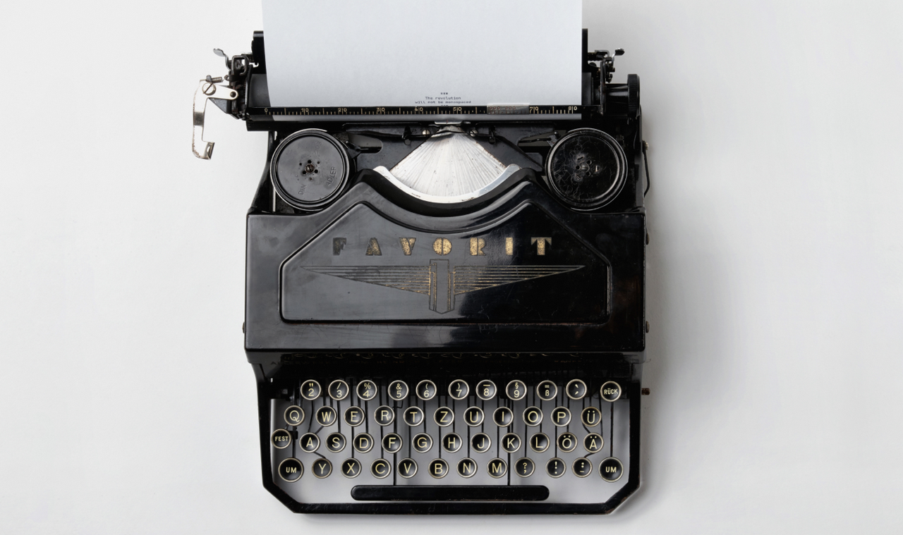 Looking down at an antique Favorit typewriter with a piece of paper sticking out of the top of it.