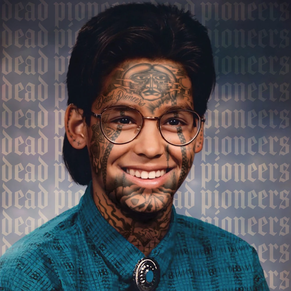 School photo of a male with glasses. He’s smiling wide and wearing a pattern button-up shirt with a bolo tie. He has various tattoos graphically added to his face. The band’s name is tiled in the background.