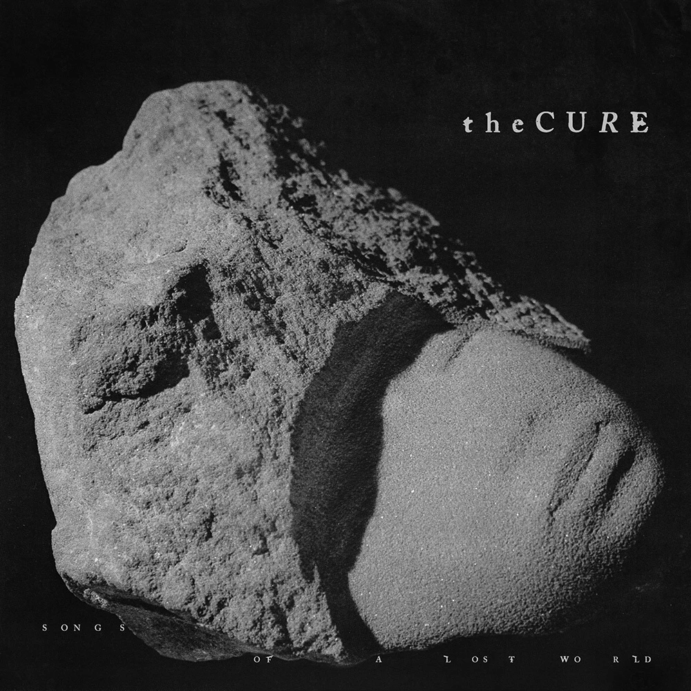 Silhouette of a partially completed stone sculpture of a human face. The band name and title are overlaid in a smudgy and misaligned font.